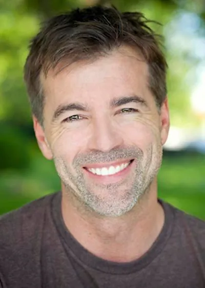 man smiling after dental crowns helped restore his smile