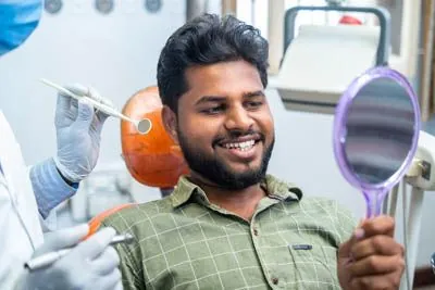 man looking at his freshly cleaned smile in the mirror